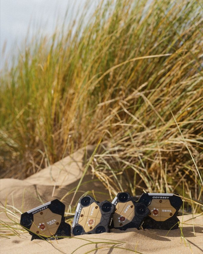 Four Odyssey TRTL putters in the sand in front of dune grass